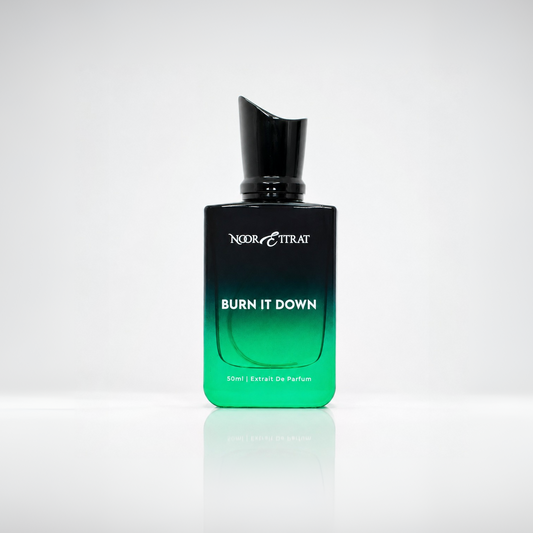 Perfume bottle labeled 'Burn It Down' by Nereis Trat on a reflective gray surface.